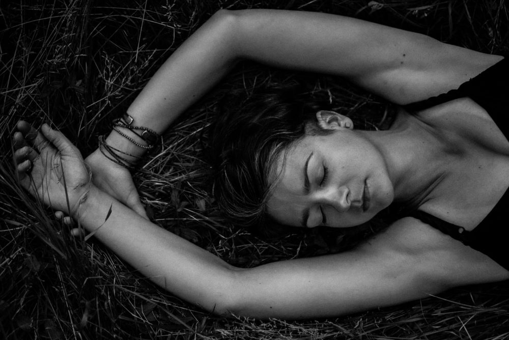 kobieta leżąca w trawie, czarno-białe zdjęcie