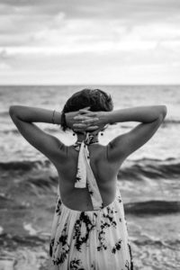 kobieta w sukience z odsłoniętymi plecami na tle morza